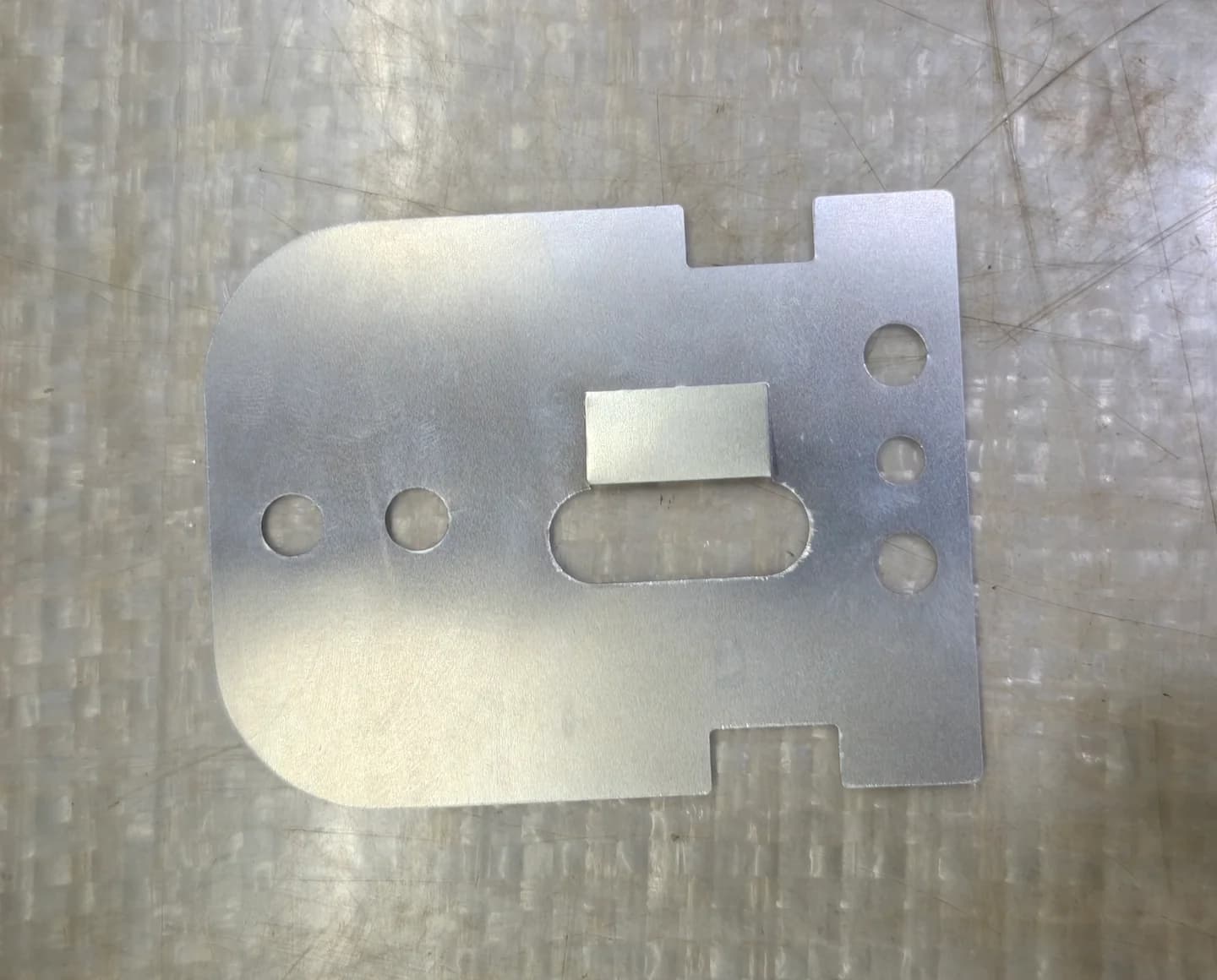 Complete formed metal part with mounting holes and a slot on a worktable