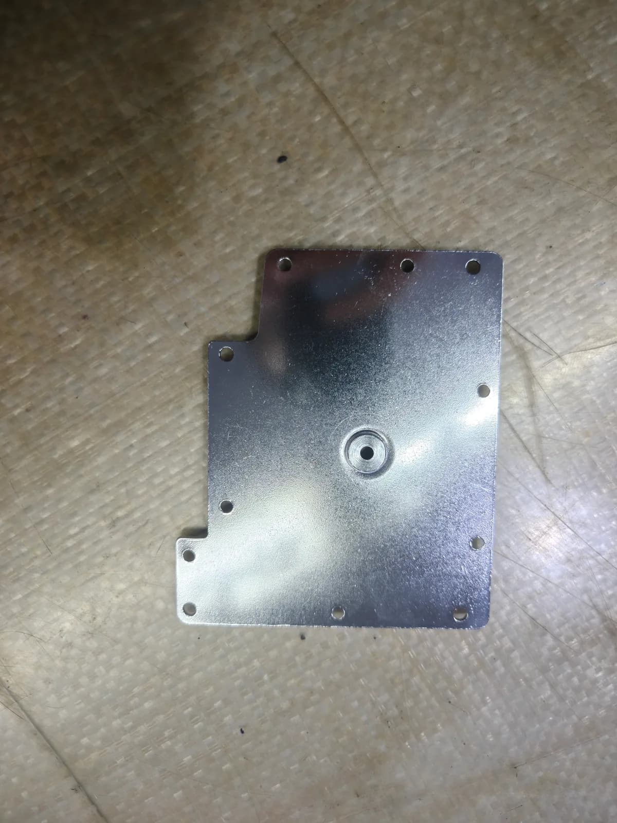 Metal mounting plate with perimeter holes and a central raised feature