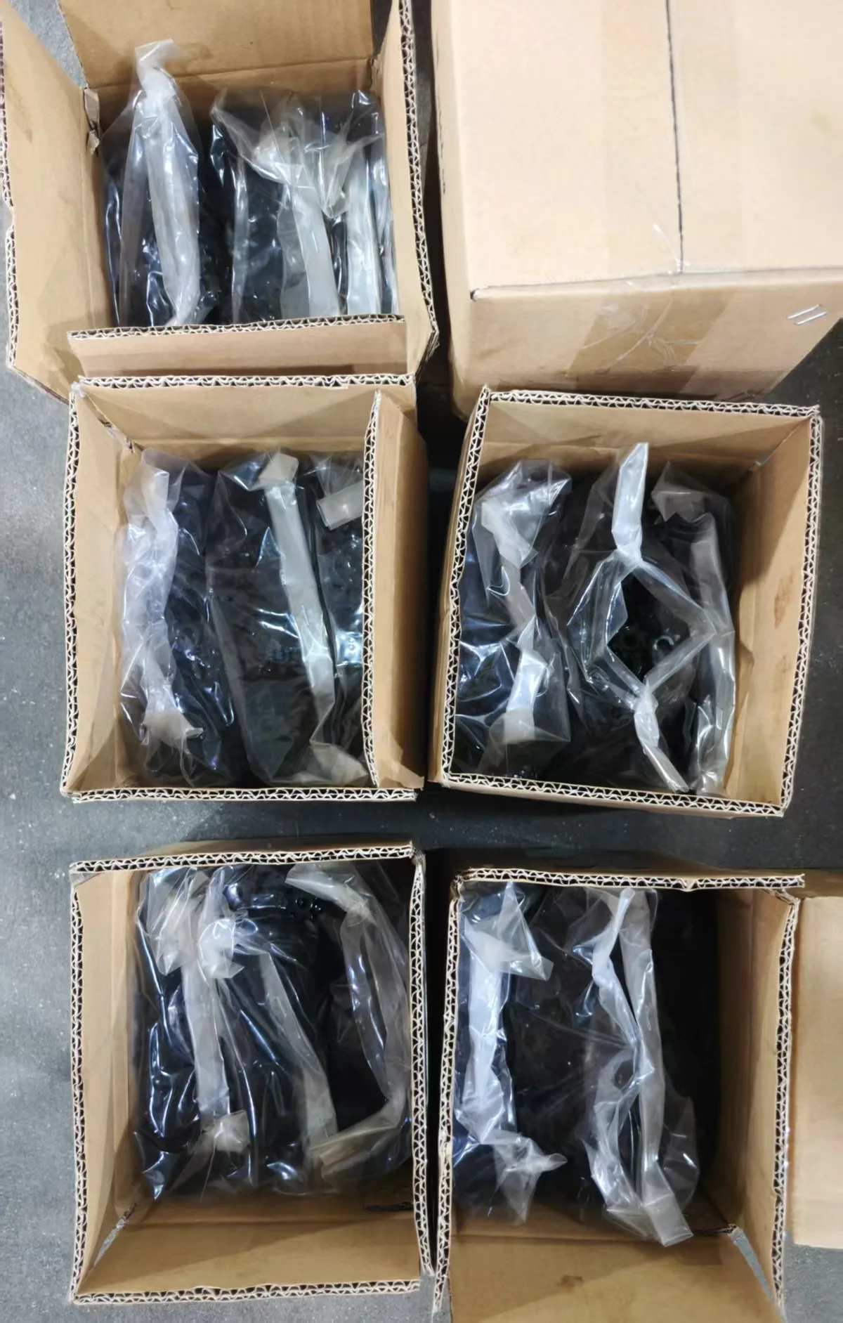 Open cartons holding inner bags of blackened stamped door lock gears at the factory