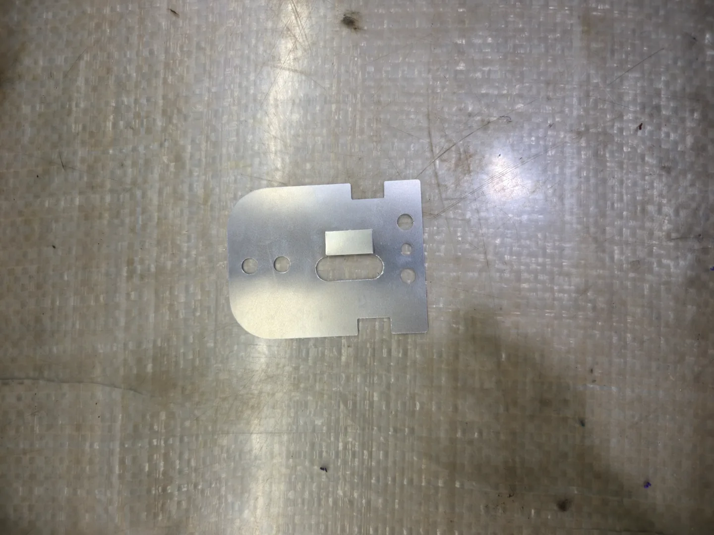 Formed metal plate with multiple holes, a slot and bent features