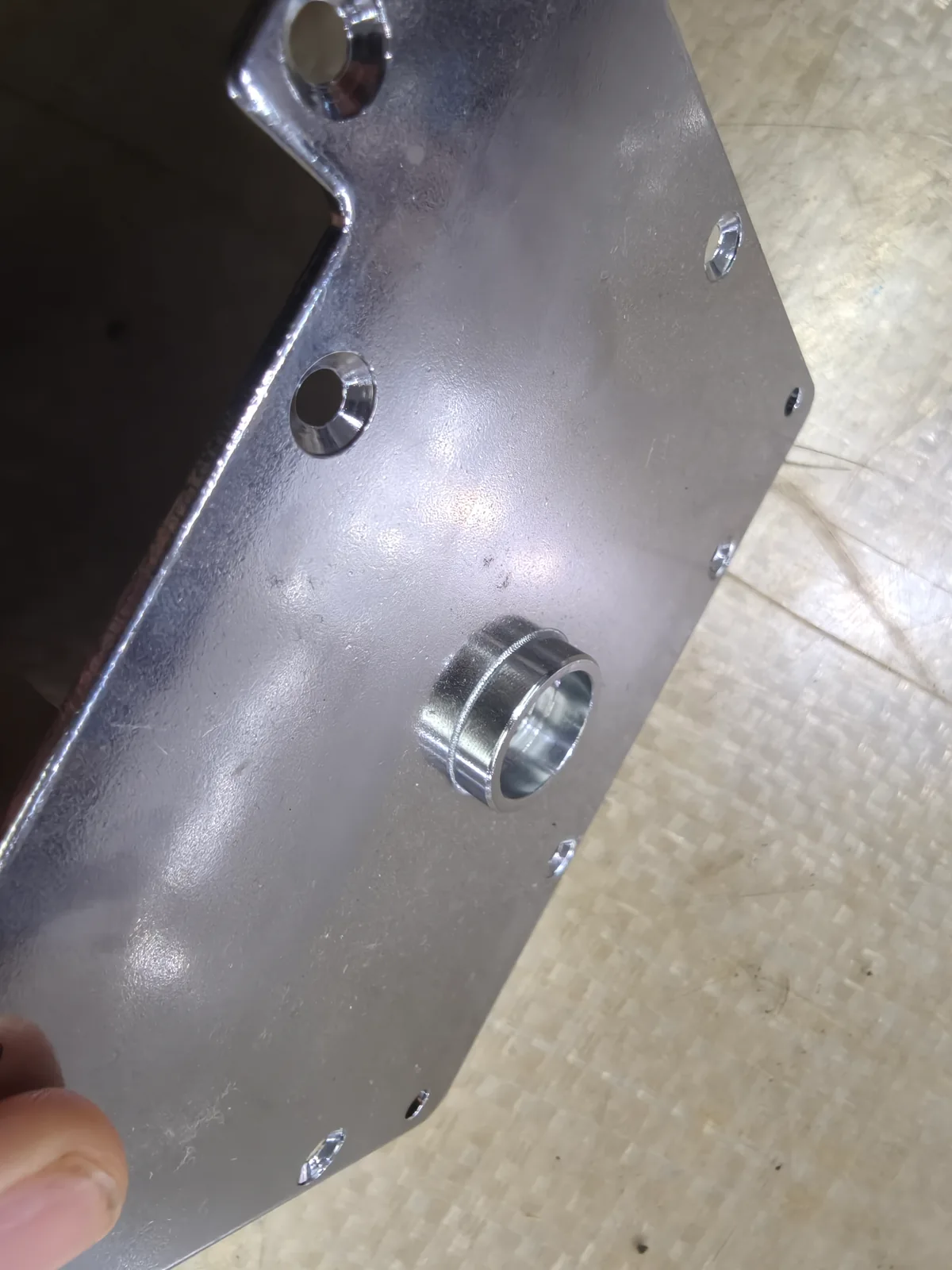 Detail of a metal mounting plate with a central projecting feature and perimeter holes
